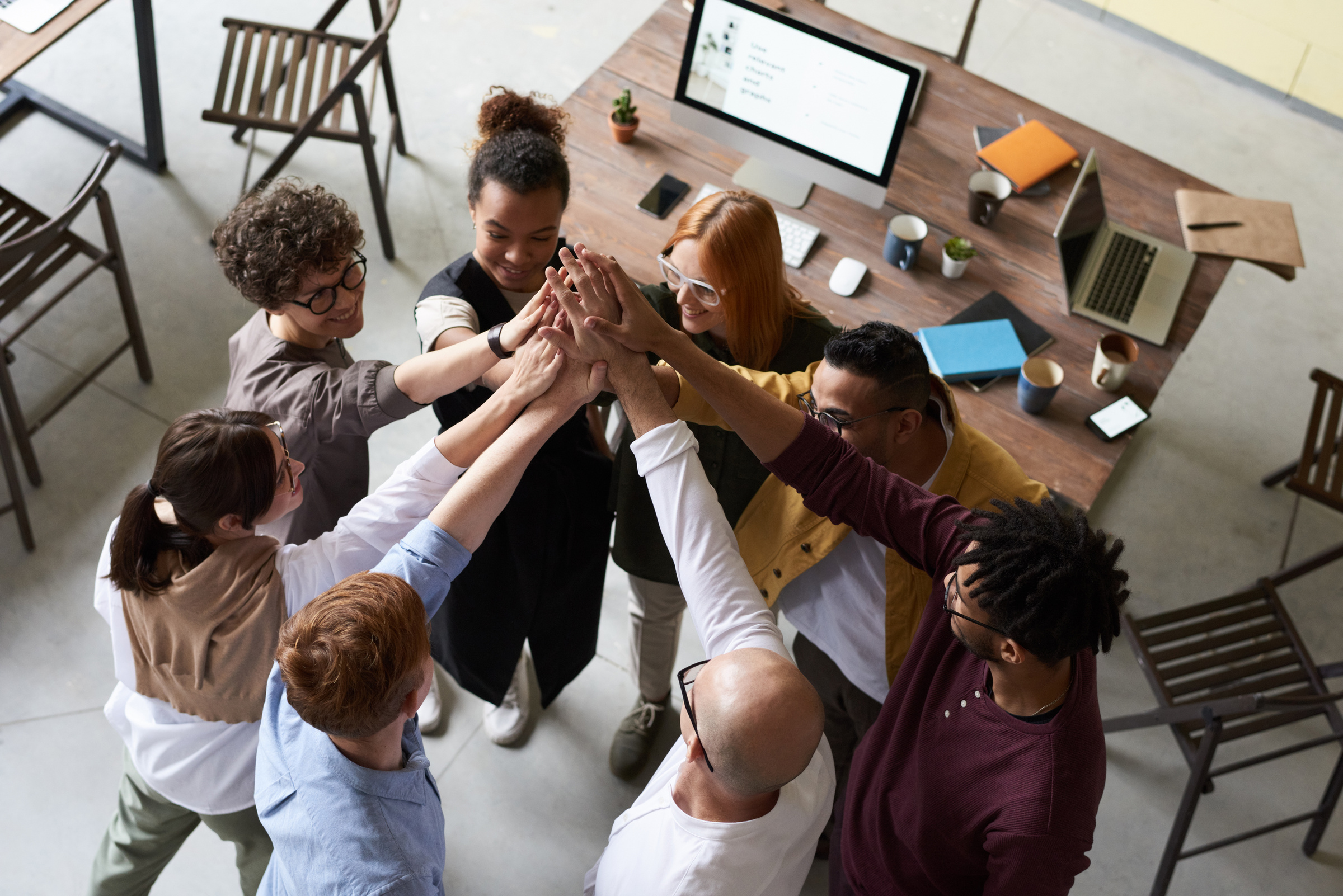 Group high five of a diverse team of employees in an office